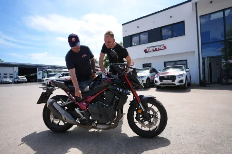 Zwei Männer prüfen ein Motorrad vor einem Autohaus